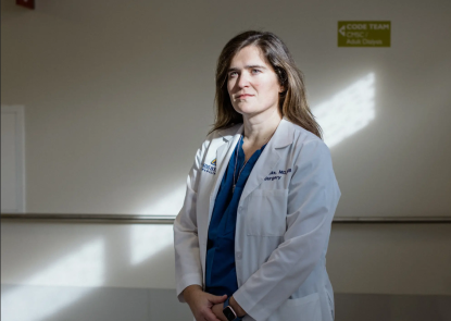 Caitlin Hicks poses for a photo while wearing her white coat at Johns Hopkins Hospital.