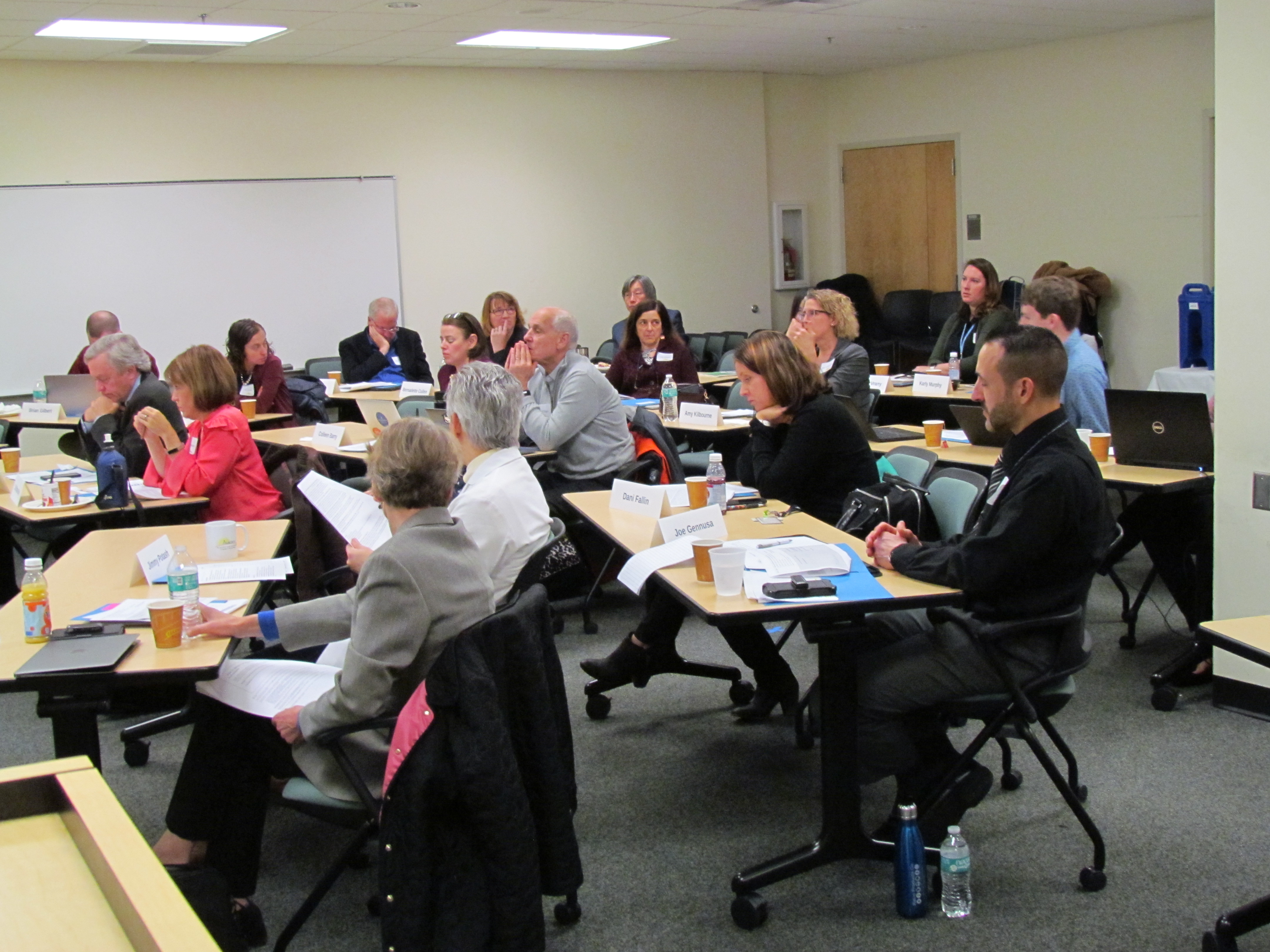 ALACRITY Center Faculty and External Advisory Board Members sitting at desks and engaged in discussion during an active meeting.