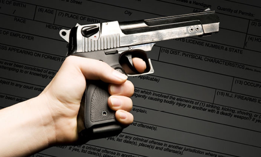 A gun held in hand superimposed over a sample permit form