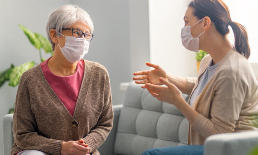 Two women wearing face masks carry on a conversation