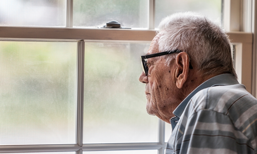 elderly man looking out of a window