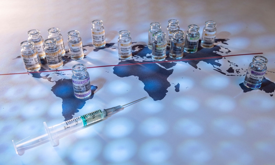 A world map with covid vaccine an syringes distributed