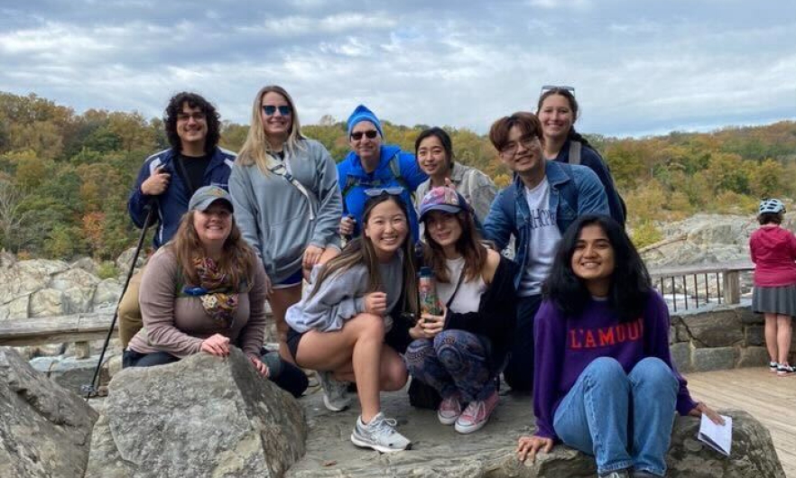 group of students pose on a rock with a natural background
