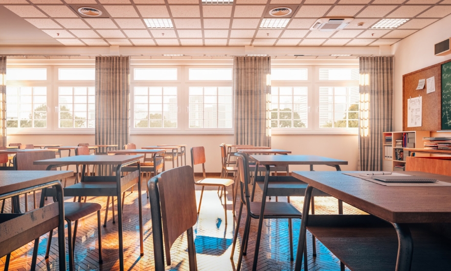 Photograph of an empty school classroom with bright light shinning through the windows.