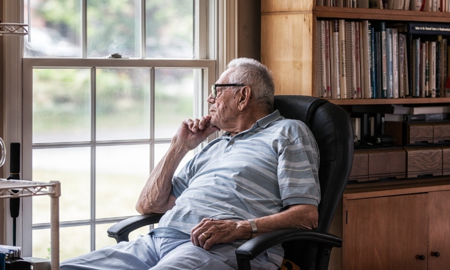 Photograph of older adult looking out a window.