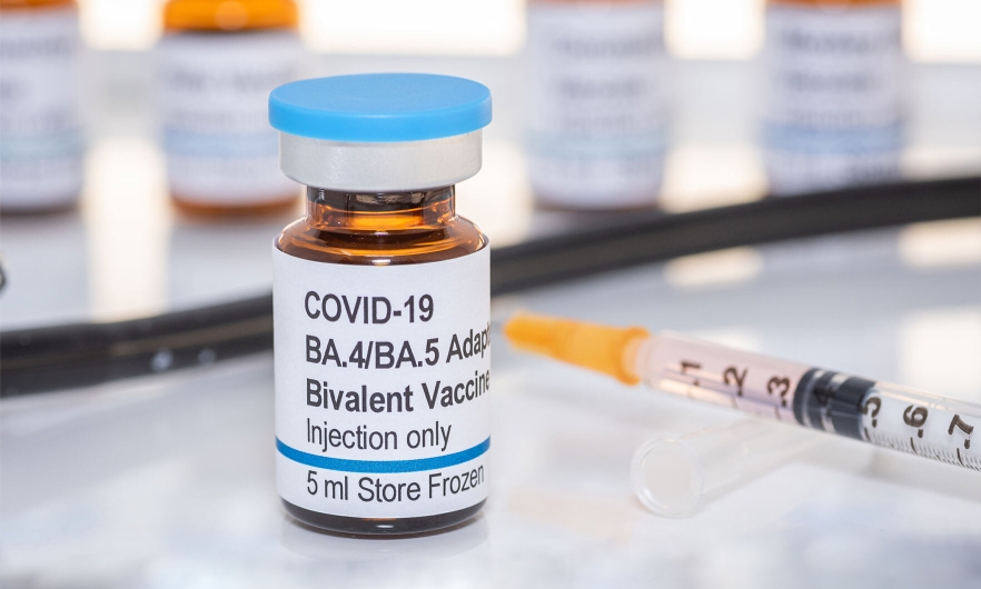 a vial labeled COVID-19 BA.4/BA.5 Bivalent Booster injection only, with a syringe next to it