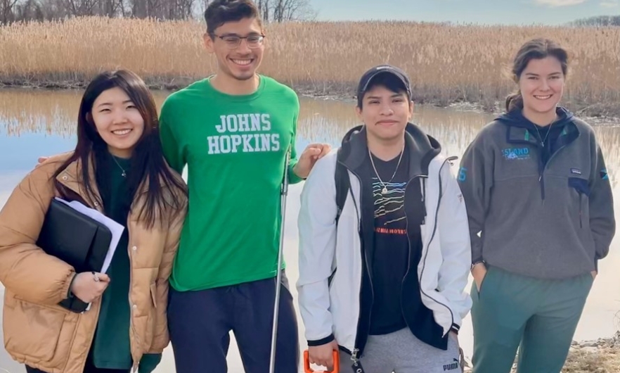 Four students standing in front of a waterway