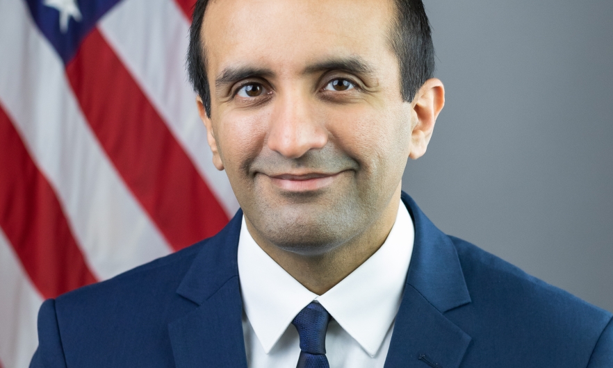 A headshot of Dr. Raj Panjabi in front of an American flag