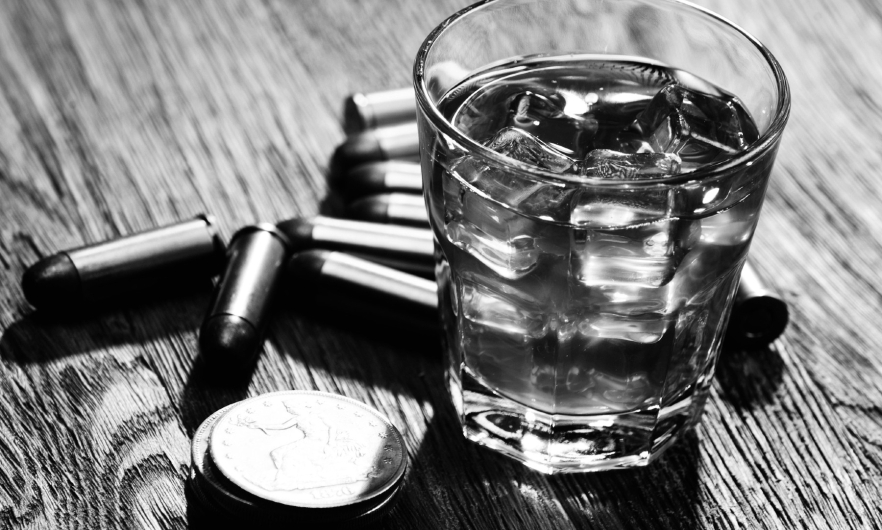 A black and white photo of an alcoholic drink with bullets sitting on a table