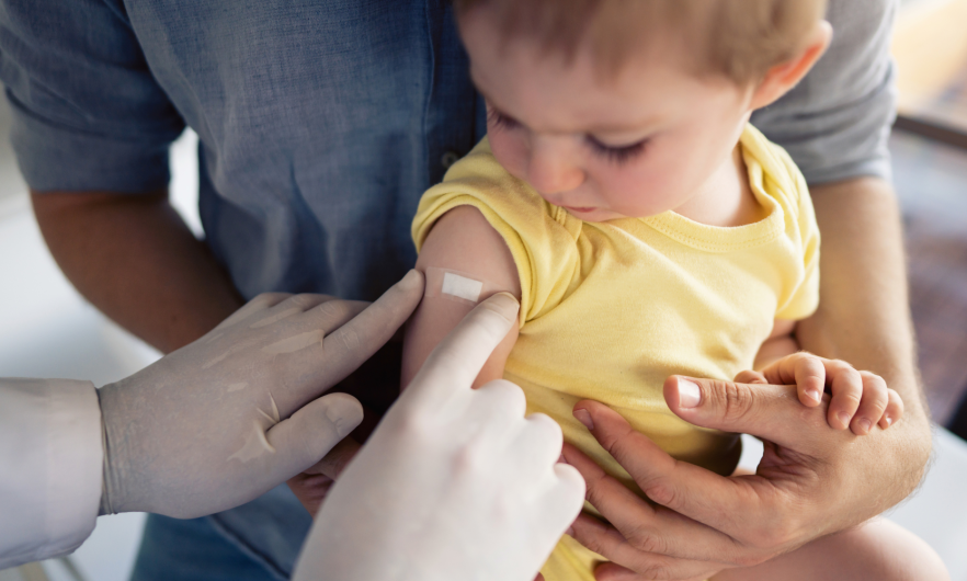 nurse placing bandaid on a child after vaccine