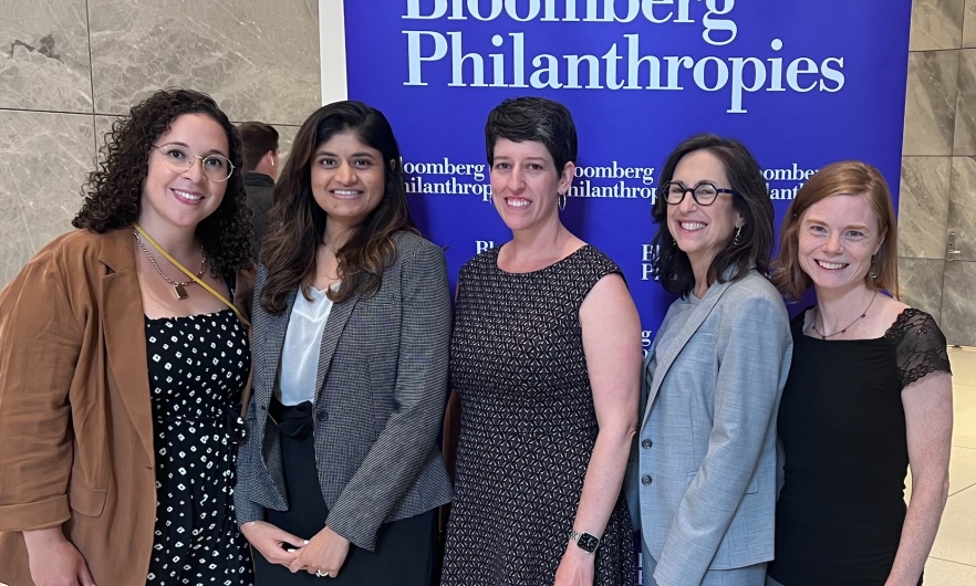 Members of the Gender Equity Unit Team pose in front of a Bloomberg Philanthropies sign at the Data for Health Partner Meeting 2023 in New York City.