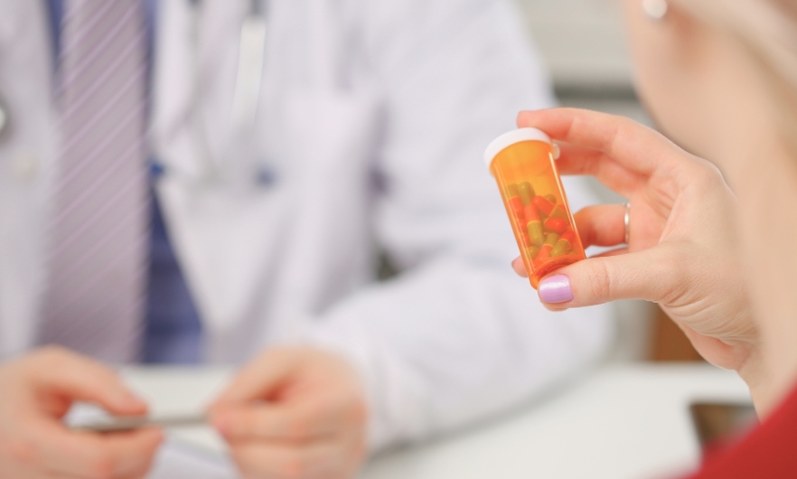 A person holding a bottle of pills in front of a physician