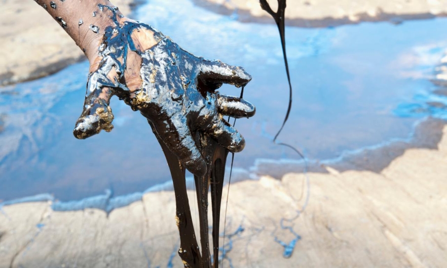 image of oil spilling though person's hand