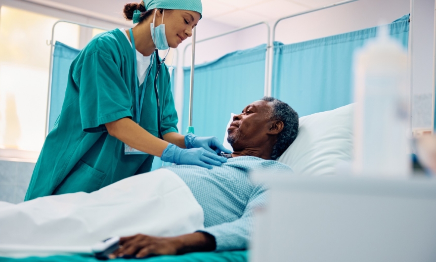 image of older Black patient in hospital bed with female nurse attending