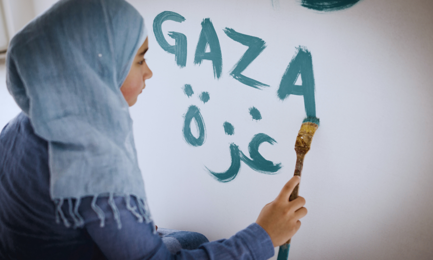Woman painting "Gaza" onto a wall