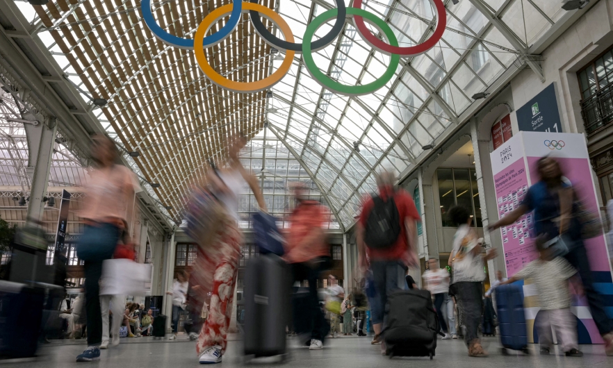 Commuters walk under the Olympic rings at the Gare de Lyon train station, on July 23, 2024, ahead of the Paris 2024 Olympic and Paralympic Games.