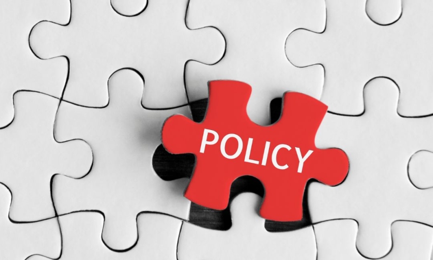 A red puzzle piece labeled policy is slotted into the last empty space of an otherwise complete, white puzzle piece grid.