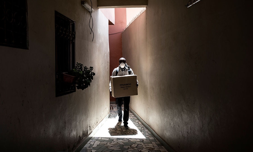 A worker carries a box of protective masks, made from a 3D printing machine, to be delivered emergency workers on the frontline of the COVID-19 coronavirus outbreak in Dakar, Senegal, on April 16, 2020. Image: John Wessels/AFP/Getty