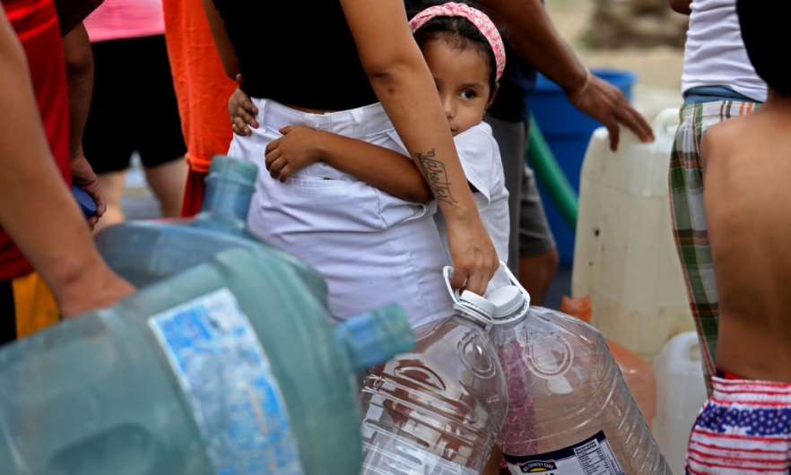 A young girl waits in line for not potable water delivered by a tanker truck in Colonia Mirador de Garcia, northwest of Monterrey, Mexico. July 19, 2022.