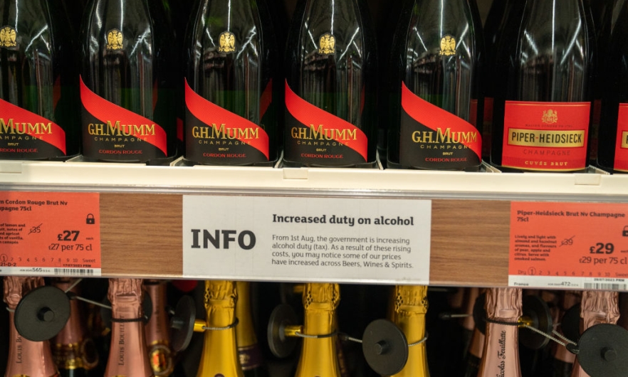 A notice is posted about a rise in duty for alcoholic beverages, between two rows of champagne bottles on store shelves, August 4, 2023 at a Sainsbury&#039;s Market in London, England. Robert Nickelsberg/Getty