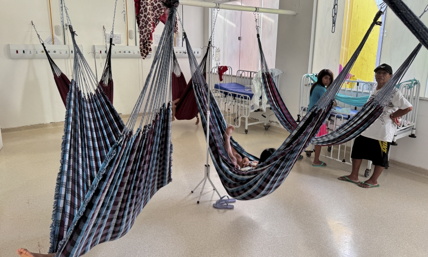 Yanomami Indigenous people rest in traditional blue and white hammocks used in lieu of hospital beds.