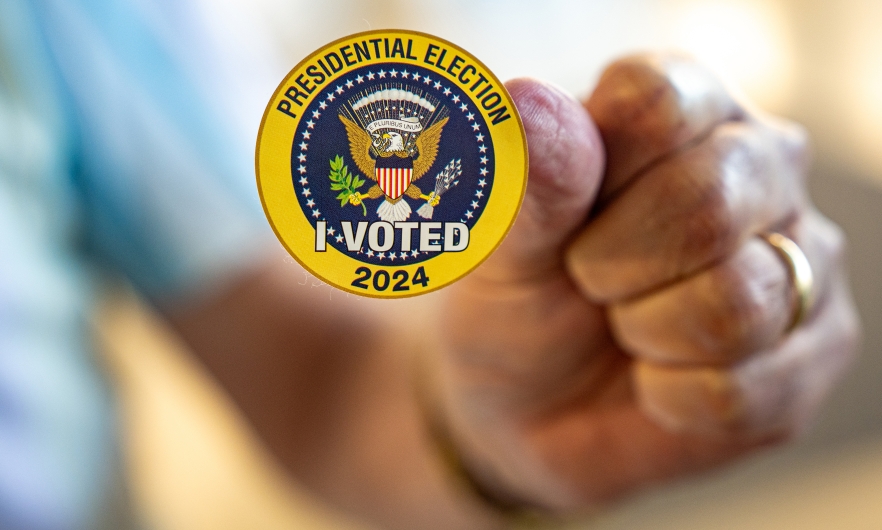 A man holds up a sticker that reads &quot;Presidential Election I Voted 2024&quot; on the first day of Virginia&#039;s in-person early voting at Long Bridge Park Aquatics and Fitness Center on September 20, 2024, in Arlington, Virginia.