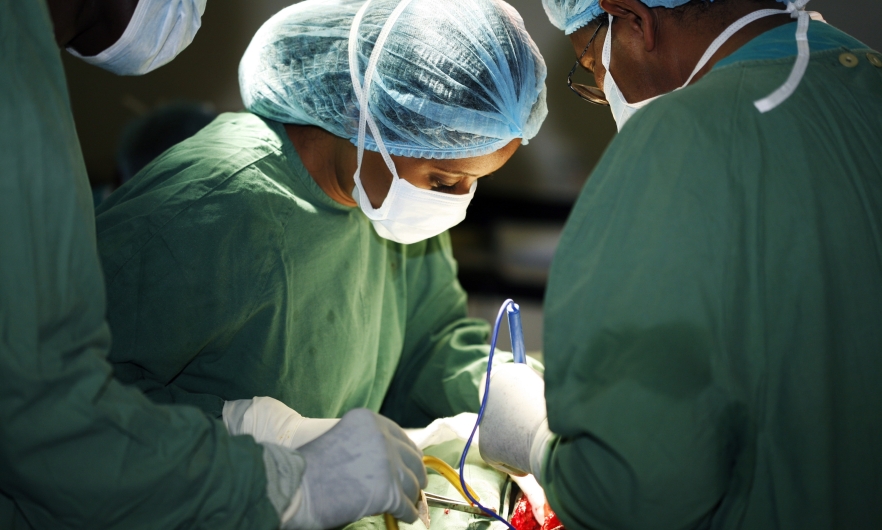 Closeup of a surgeon in green scrubs and her assistants operating on a patient. Universal Images Group Getty