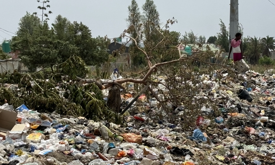 A girl walks among the mountains of waste in Garden Compound.