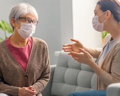 Two women wearing face masks carry on a conversation
