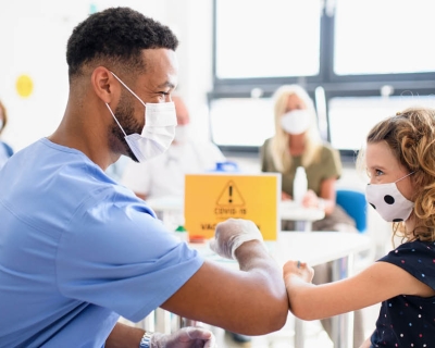 Doctor touching elbows with young patient