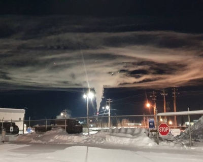 a circular plume in a night sky over a lighted, snowy area