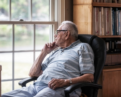 Photograph of older adult looking out a window.