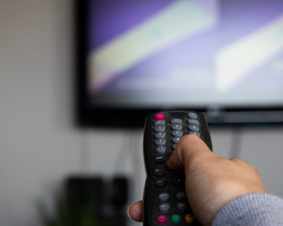 Person aiming remote control at television