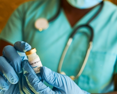 Close-up of a medical provider's gloved hands holding a vaccine vial