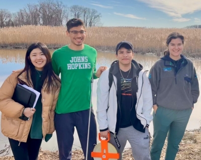 Four students standing in front of a waterway