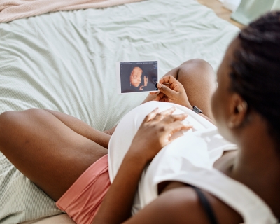 Black pregnant woman holding a sonogram