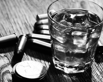 A black and white photo of an alcoholic drink with bullets sitting on a table