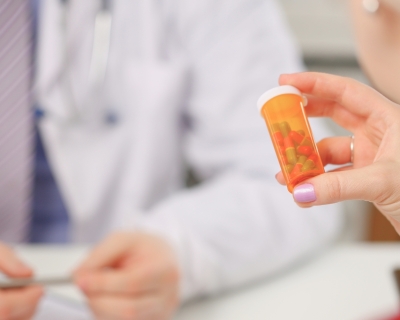 A person holding a bottle of pills in front of a physician