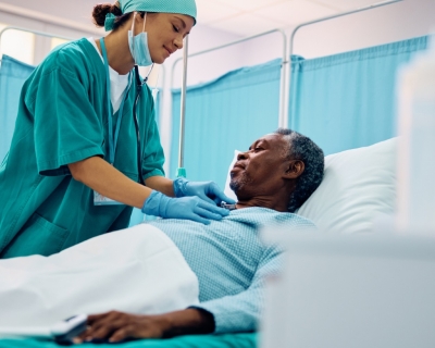 image of older Black patient in hospital bed with female nurse attending