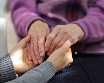 A youthful pair of hands holds an elderly pair of hands