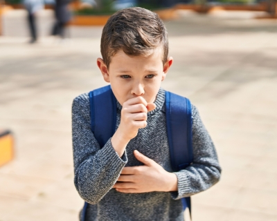 child coughing into hand outside school