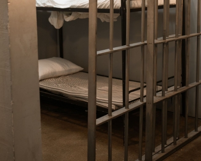 A jail cell with the bar doors opened halfway. A bunk bed is visible behind the bar door.