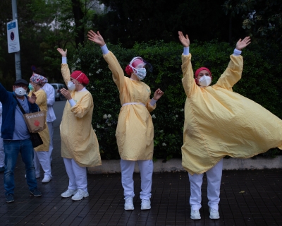 Several health care workers wearing face masks and yellow protective suits acknowledge applause outside the Hospital de Barcelona on April 13, 2020 in Barcelona, during a national lockdown to prevent the spread of the COVID-19 disease. 