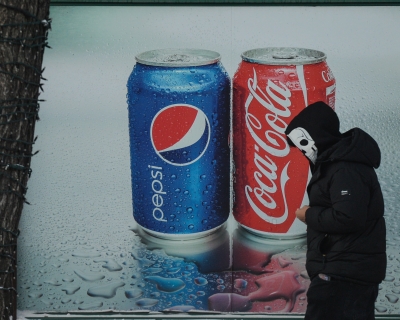 A man wearing a skull face mask walks past a Pepsi and Coca-Cola ad in the center of Edmonton, Alberta, Canada. December 30, 2021. 