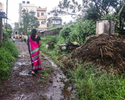 ASHA Shubhangi Kamble walking through a dirty patch of mud during heavy rainfall to a community member’s house whose child fell sick. 
