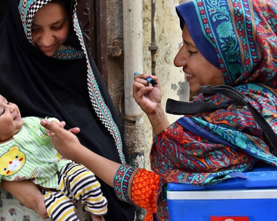 A woman gives a polio vaccine to baby.