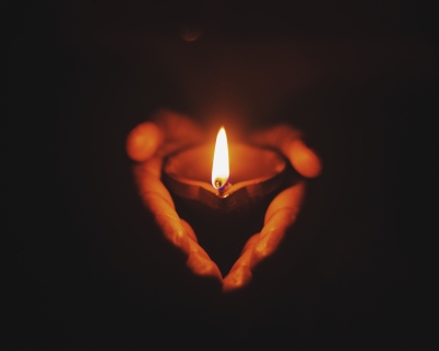 Two hands holding a lit candle.