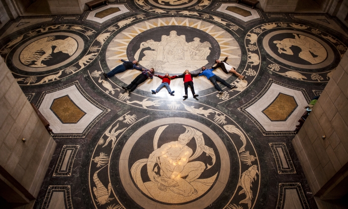 A tour group lays in a row on the decorative Rotunda floor in the Nebraska State Capitol, in Lincoln, Nebraska.