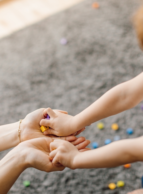 Young boy places small cubes into hands of woman