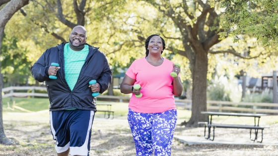 A man and a woman running and exercising in a park on a sunny day.